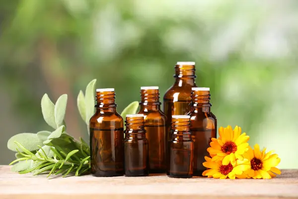 Bottles Essential Oils Herbs Flowers Wooden Table Blurred Green Background — Stock Photo, Image