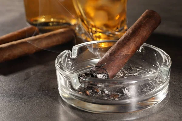 Schwelende Zigarre Aschenbecher Und Whiskey Auf Grauem Tisch Nahaufnahme — Stockfoto