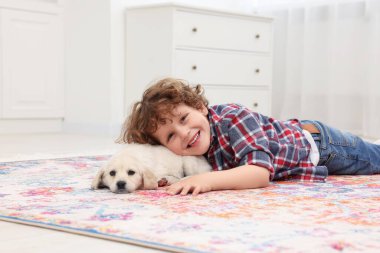 Küçük çocuk evde tatlı bir köpek yavrusuyla yatıyor.