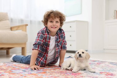 Küçük çocuk evde tatlı bir köpek yavrusuyla yatıyor.