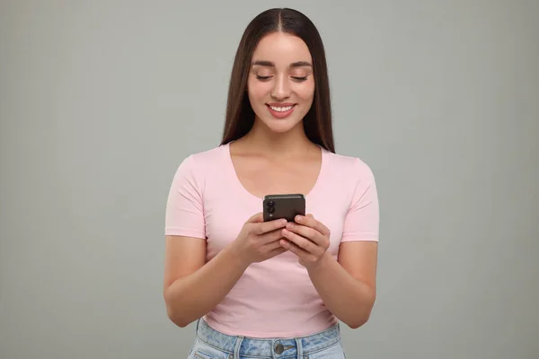 Щаслива Молода Жінка Використовує Смартфон Світло Сірому Фоні — стокове фото