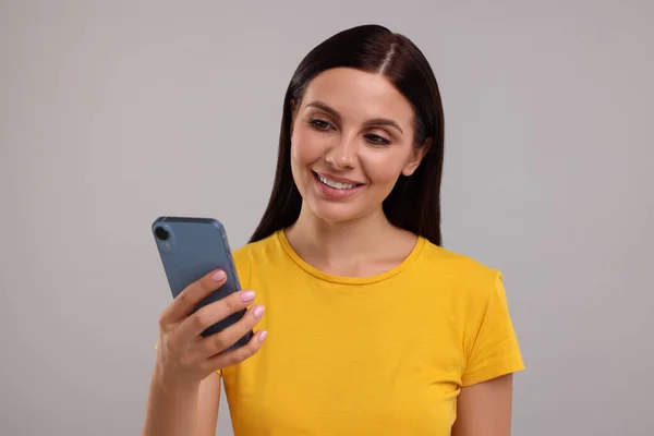Jovem Mulher Usando Smartphone Fundo Cinza — Fotografia de Stock