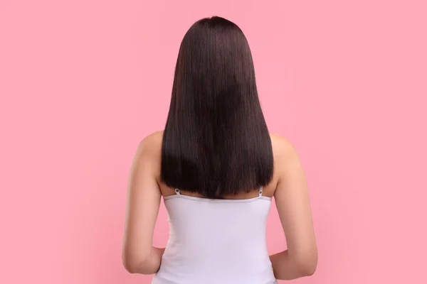 Woman with healthy hair on pink background, back view
