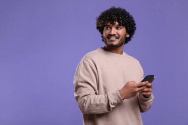 Menekşe arkaplan üzerinde akıllı telefon kullanan yakışıklı adam, metin için boşluk