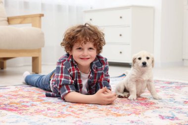 Küçük çocuk evde tatlı bir köpek yavrusuyla yatıyor.