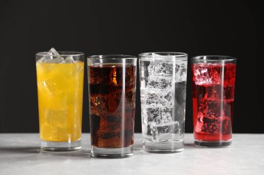 Beyaz mermer masanın üzerinde buz küpleri olan farklı tazeleyici soda bardakları.