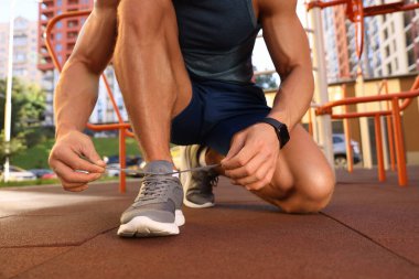Spor salonunda antrenmandan önce ayakkabı bağcıklarını bağlayan adam, yakın plan.