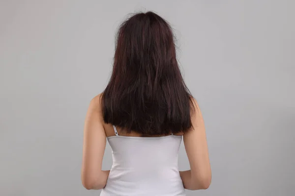 ライトグレーの背景 バックビューで髪を損傷した女性 — ストック写真