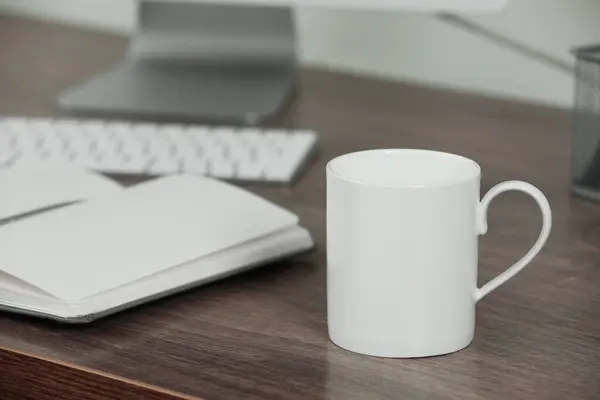 stock image White ceramic mug on wooden table at workplace. Mockup for design