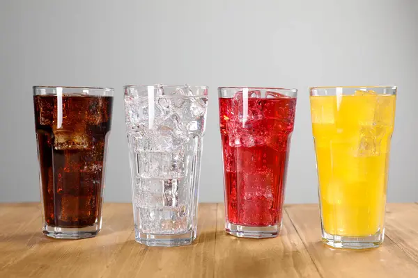 Gläser Mit Verschiedenen Erfrischungsgetränken Mit Eiswürfeln Auf Holztisch — Stockfoto