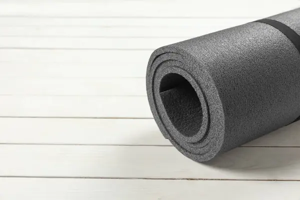 Yoga mat on white wooden floor, closeup. Space for text
