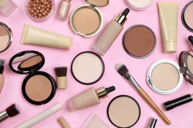 Pembe zemin üzerinde yüz pudraları ve diğer dekoratif kozmetik ürünler, düz uzanma