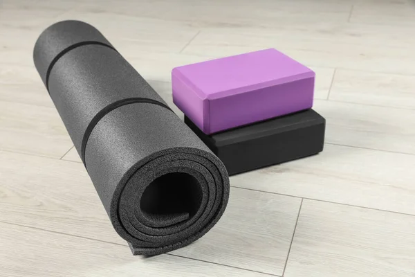 Exercise mat and yoga blocks on light wooden floor