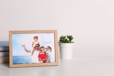 Aile fotoğrafı ve yeşil çiçekli çerçeve beyaz masada, metin için boşluk