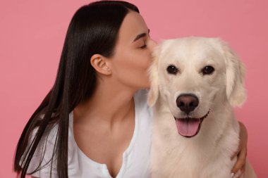 Pembe arka planda şirin Labrador Retriever köpeği olan bir kadın. Sevimli hayvan.