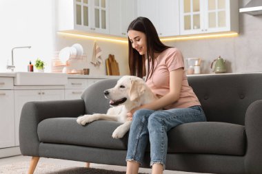 Evdeki kanepede sevimli Labrador Retriever köpeği olan mutlu kadın. Sevimli hayvan.