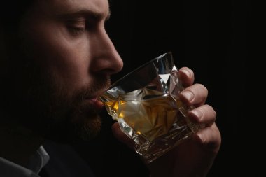 Siyah arka planda viski içen adam, yakın plan.
