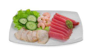 Sashimi seti (çiğ ton balığı, yağlı balık ve karides dilimleri) beyaz üzerinde salatalık, marul ve vasabi ile servis edilir.