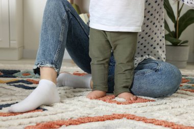 Anne oğluyla birlikte yumuşak halıda, kapalı yerde, yakın plan.