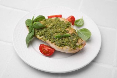 Pesto soslu leziz tavuk göğsü, beyaz masada domates ve fesleğen, yakın plan.