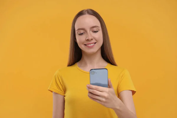 Ευτυχισμένη Νεαρή Γυναίκα Που Χρησιμοποιεί Smartphone Κίτρινο Φόντο — Φωτογραφία Αρχείου