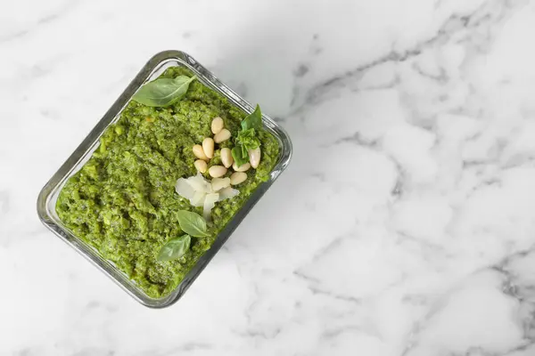 stock image Delicious pesto sauce in bowl on white marble table, top view. Space for text