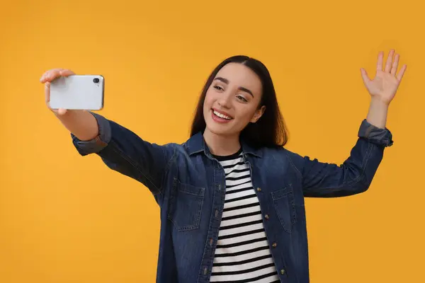 Uśmiechnięta Młoda Kobieta Robi Selfie Smartfonem Żółtym Tle — Zdjęcie stockowe
