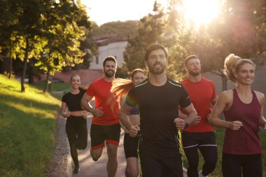 Güneşli bir günde dışarıda koşan bir grup insan.