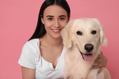 Pembe arka planda şirin Labrador Retriever köpeği olan mutlu bir kadın. Sevimli hayvan.