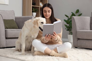 Evde sevimli Labrador Retriever köpeğiyle kitap okuyan bir kadın. Sevimli hayvan.