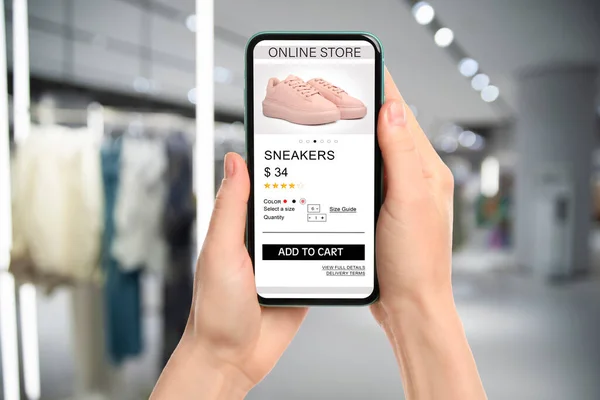 Woman visiting shop to take ordered shoes indoors, closeup. Online store website on device screen