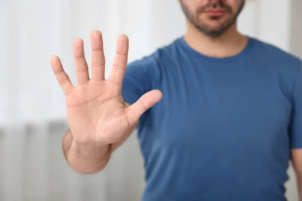 Man showing stop gesture indoors, closeup view