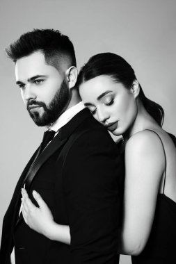 Gri arka planda seksi bayan olan yakışıklı sakallı adam. Siyah ve beyaz etkisi