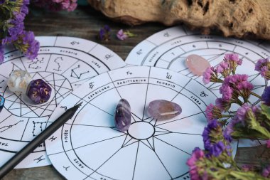 Zodyak tekerlekleri, değerli taşlar, çiçekler ve astroloji zarları ahşap masada, yakın plan.