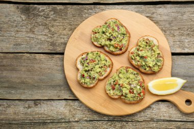 Lezzetli guacamole soslu ekmek dilimleri ve ahşap masada limon, üst manzara. Metin için boşluk