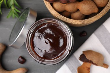 Lezzetli tamarind sosu kavanozu ve gri ahşap masa üzerinde taze kapsüller.