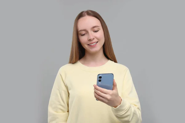 Happy Jonge Vrouw Met Behulp Van Smartphone Lichtgrijze Achtergrond — Stockfoto