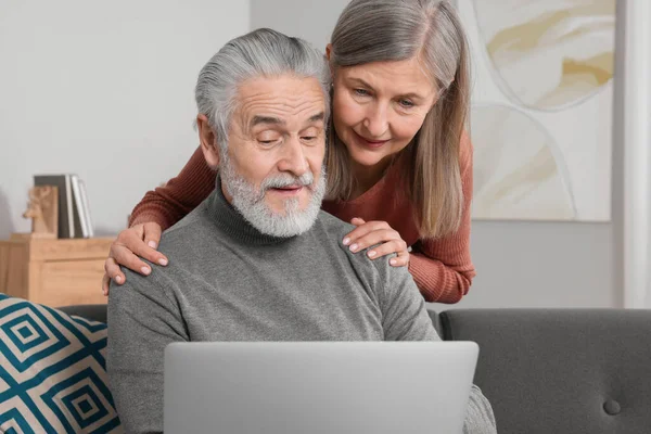 Elderly couple with laptop discussing pension plan in room