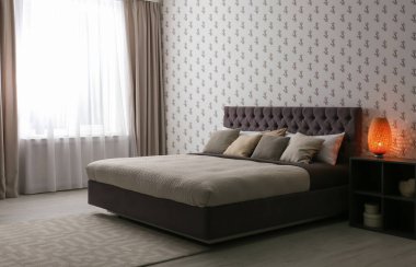 Minimalist yatak odası. Pencerenin yanında geniş yatak var.