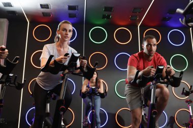 Spor salonunda egzersiz bisikleti eğitimi alan bir grup insan.