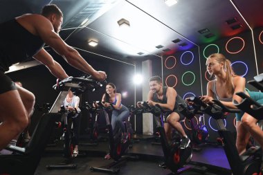 Spor salonunda egzersiz bisikleti eğitimi alan bir grup insan.