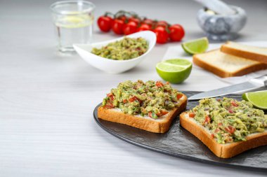 Beyaz ahşap masada guacamole soslu lezzetli sandviçler. Metin için boşluk