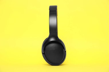 Sarı arka planda modern siyah kablosuz kulaklıklar