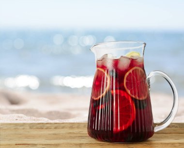 Deniz kenarındaki ahşap masada Red Sangria tazeleniyor, metin için yer var.