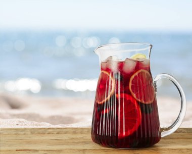 Refreshing Red Sangria on wooden table near sea, space for text clipart