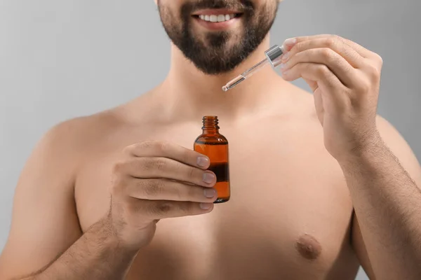 Man Met Cosmetisch Serum Handen Lichtgrijze Achtergrond Close — Stockfoto
