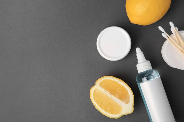 Lemon face cleanser. Fresh citrus fruits and personal care products on dark grey background, flat lay. Space for text