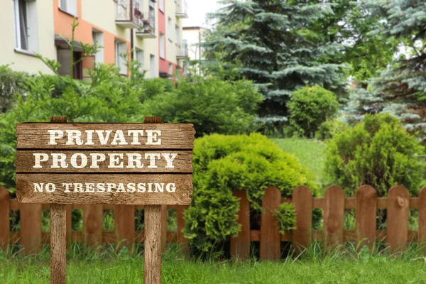 Wooden sign with text Private Property No Trespassing near house