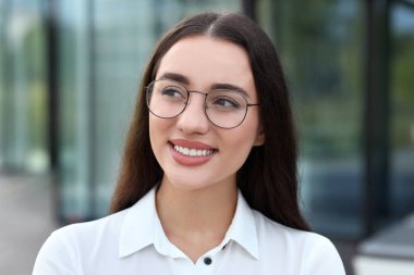 Açık havada gözlüklü güzel bir kadının portresi. Çekici bayan gülümsüyor ve kameraya poz veriyor.