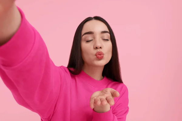 Młoda Kobieta Robi Selfie Wieje Pocałunek Różowym Tle — Zdjęcie stockowe